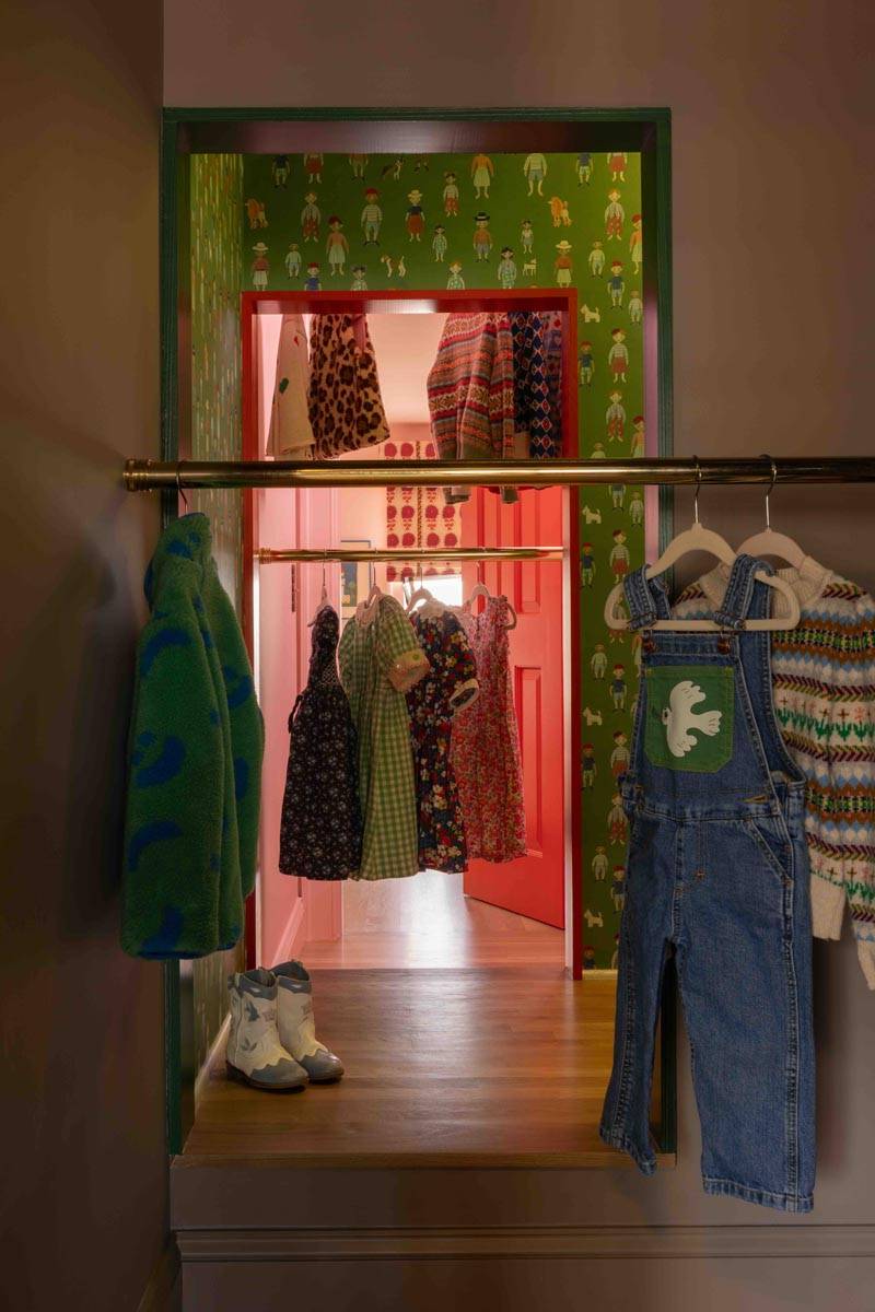 Playful walk-in closet photoshoot space with green wall paneling and open clothing racks in a Brooklyn townhouse from Love Locations.