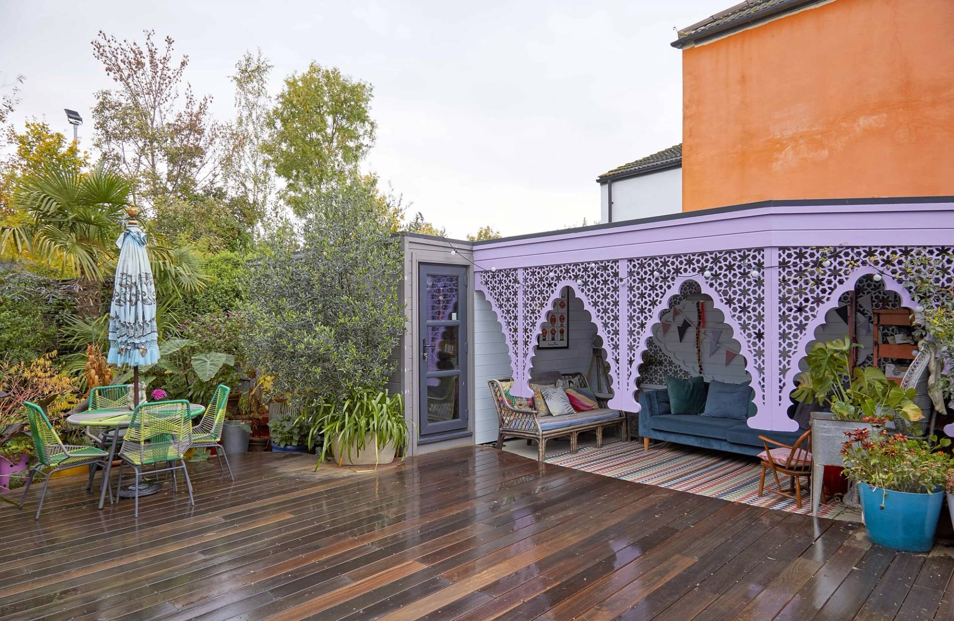 Lush garden deck corner with purple carved arch verandas and green potted tropical plants, Love Locations SE6.