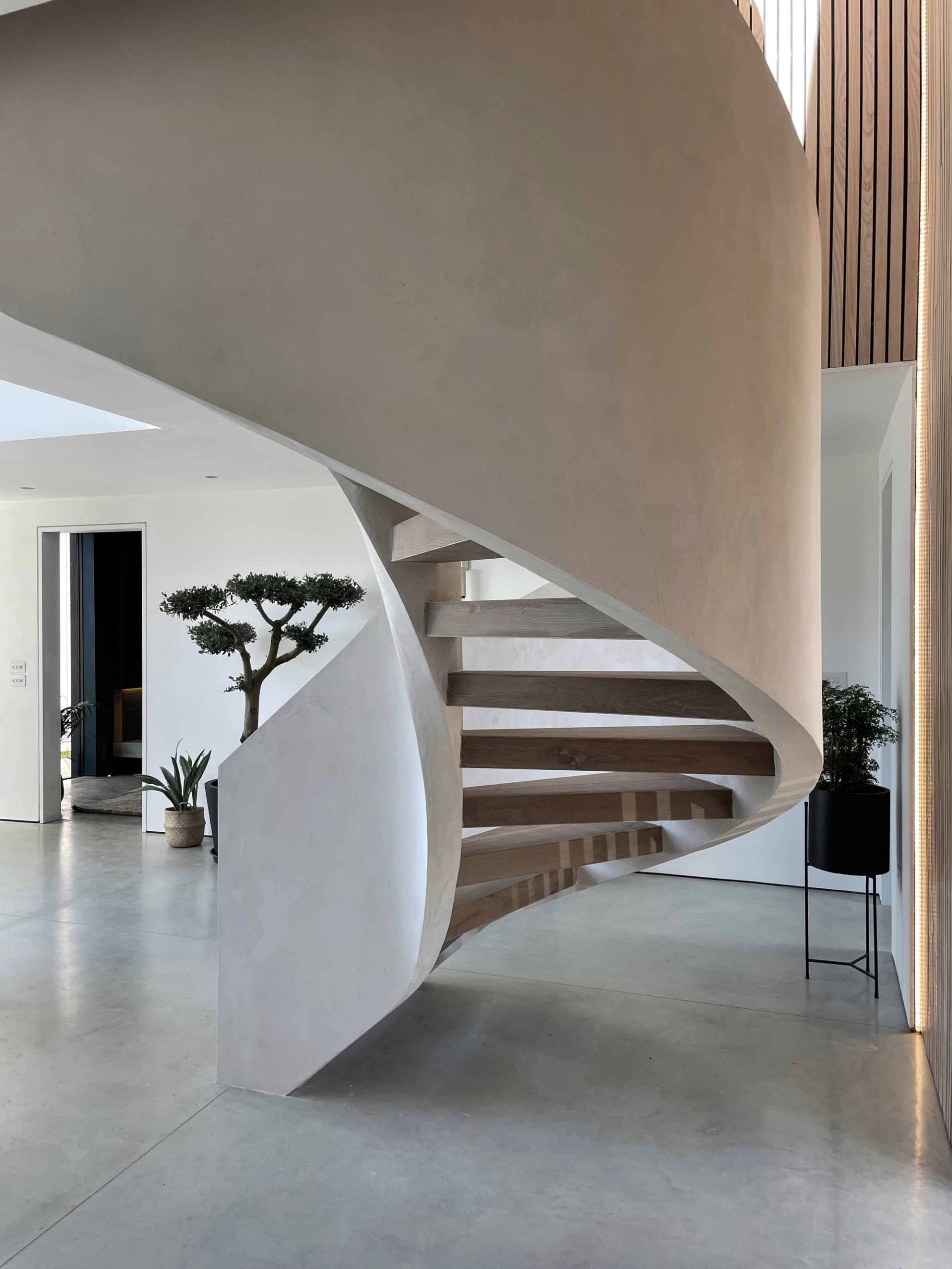 Bespoke plaster helical spiral staircase with light timber steps set on polished concrete floors, ideal for high-concept architectural and fashion photography, Love Locations.