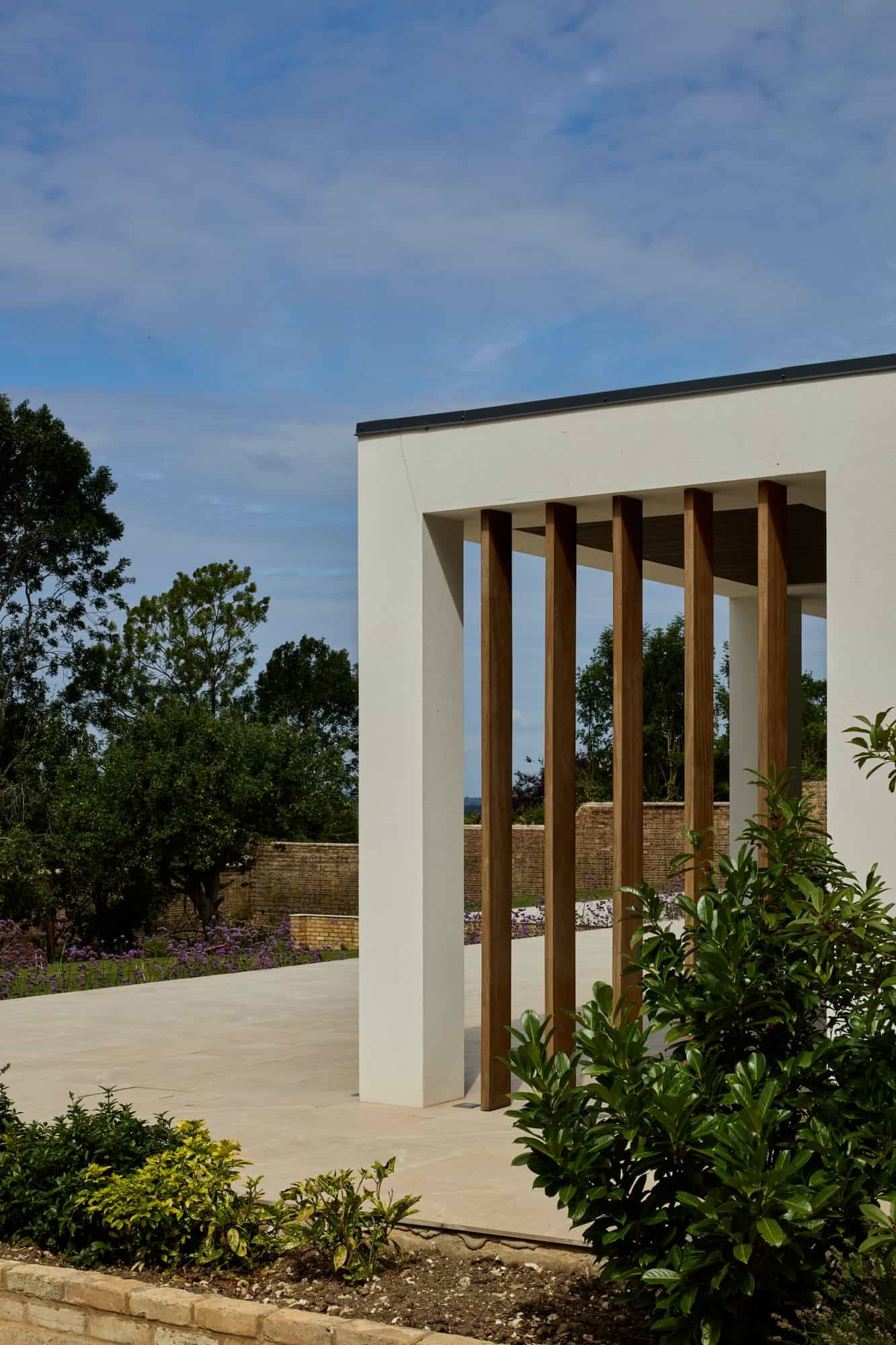 Architectural detail of modern white portico framing vertical timber louvres and landscaped entry gardens, Love Locations.