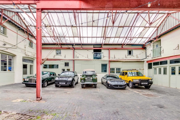 Retro supercar shoot location featuring classic cars under a covered industrial glass-roof structure, via Love Locations Richmond.