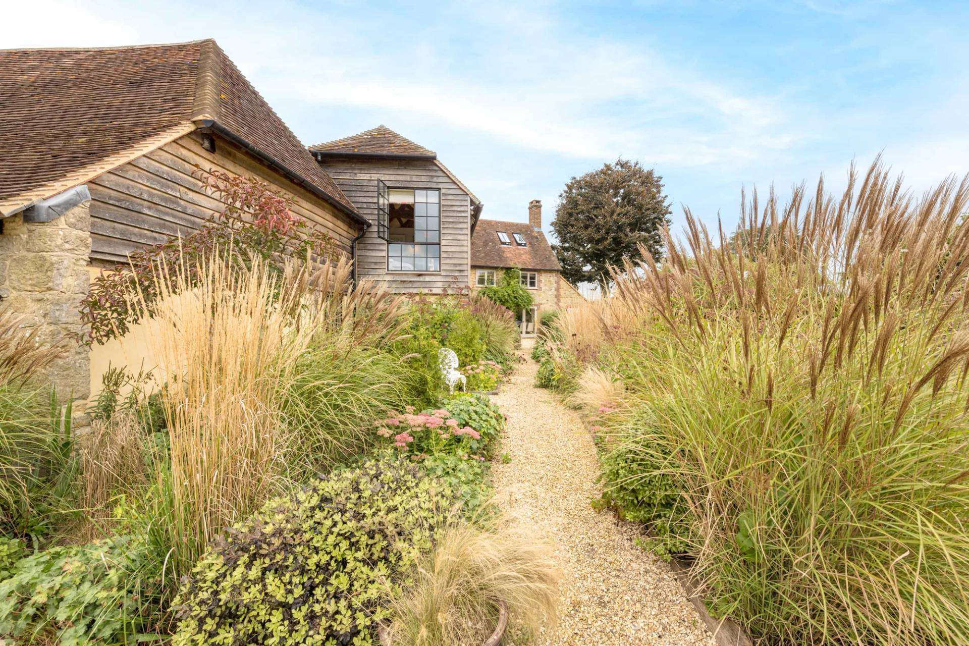 Winding gravel walkway through prairie-style planting and ornamental grasses in a West Sussex garden, Love Locations GU28.