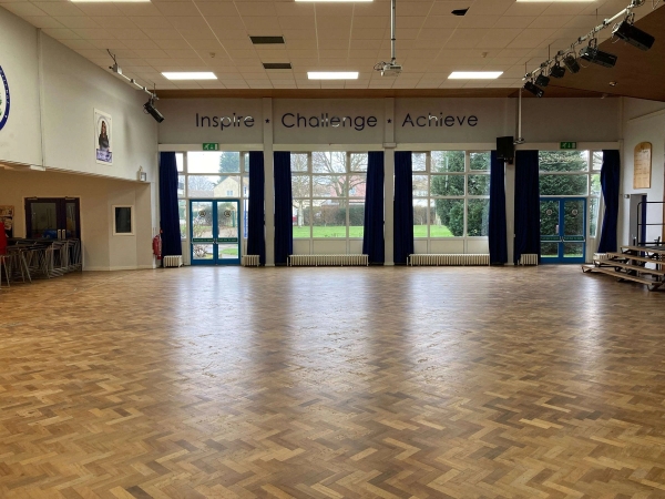 Love Locations versatile school hall location CM1: Spacious multi-purpose hall with a polished parquet wood floor and expansive windows looking outside, perfect for crowd scenes, background extras, and commercial filming.