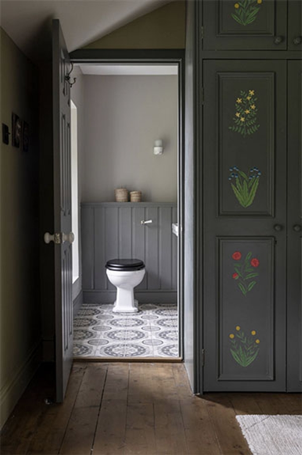 Glenstriven bedroom wardrobe panelled with painted flowers beside en-suite bathroom door and wood floor.