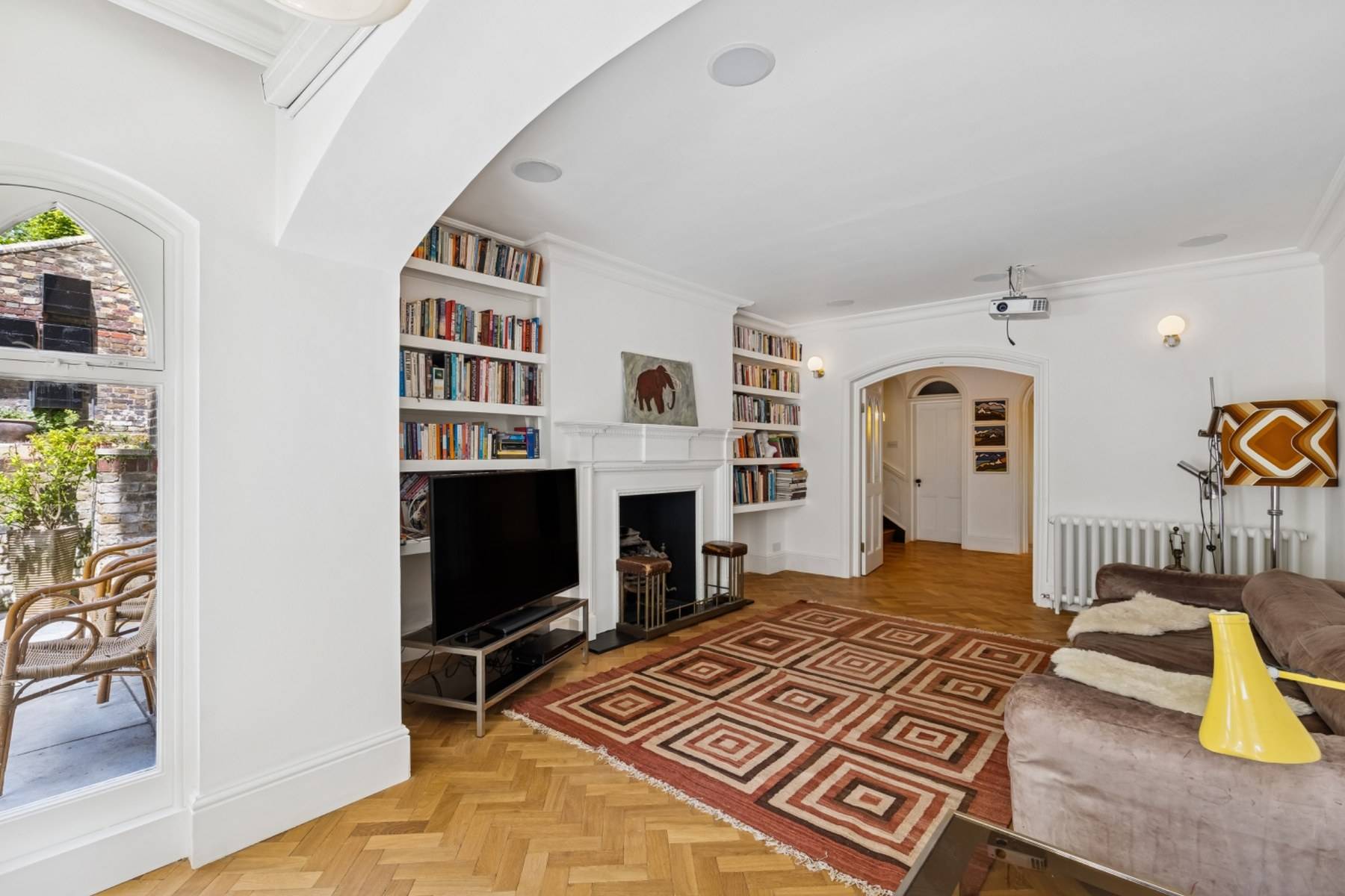 Spacious reception room with white walls, parquet floor, and built-in bookcases in Hampstead NW3 through Love Locations.