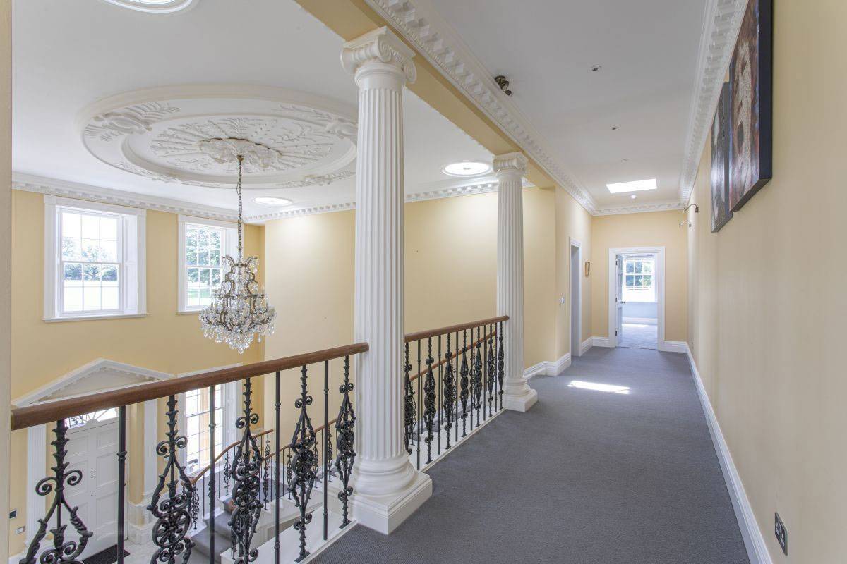 Spacious, light-filled upper hallway with architectural columns and period details for commercial filming, available through Love Locations.
