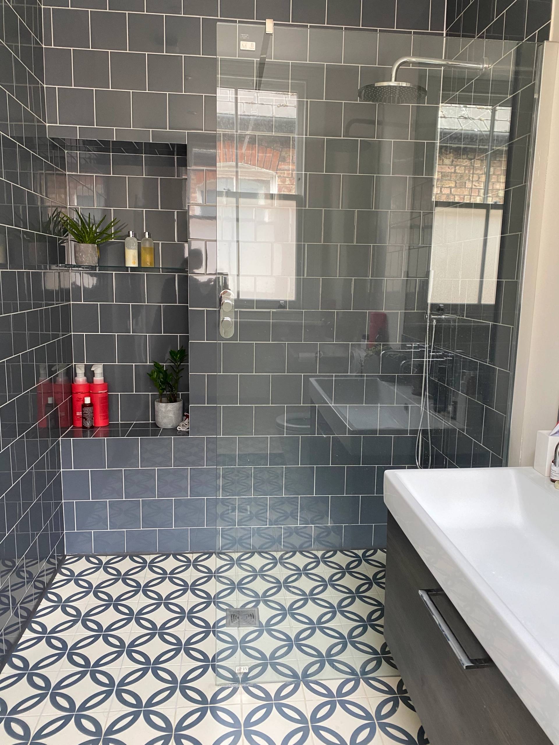 Contemporary walk-in shower room with dark grey square wall tiles and monochrome patterned floor tiles, Love Locations.