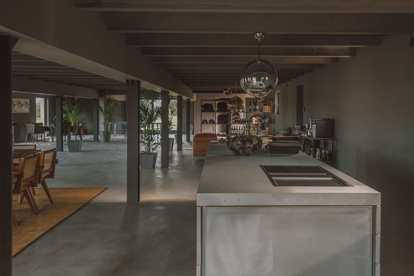 Open-plan reception room featuring exposed ceiling beams, polished concrete floors, and kitchen prep island, Love Locations 07630.