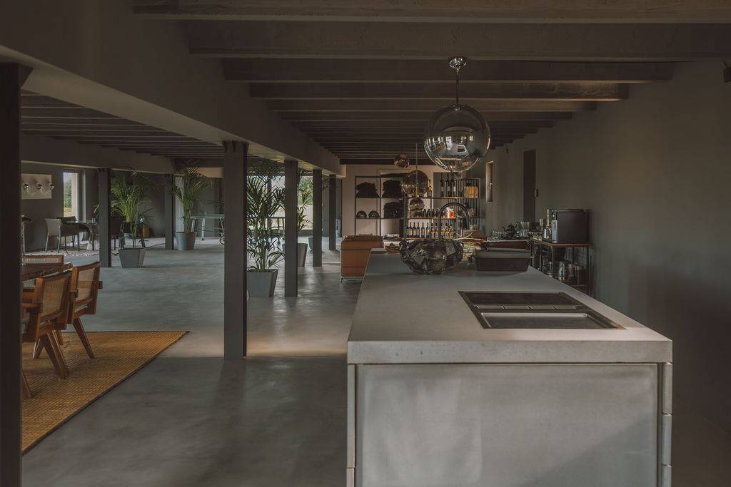 Open-plan reception room featuring exposed ceiling beams, polished concrete floors, and kitchen prep island, Love Locations 07630.