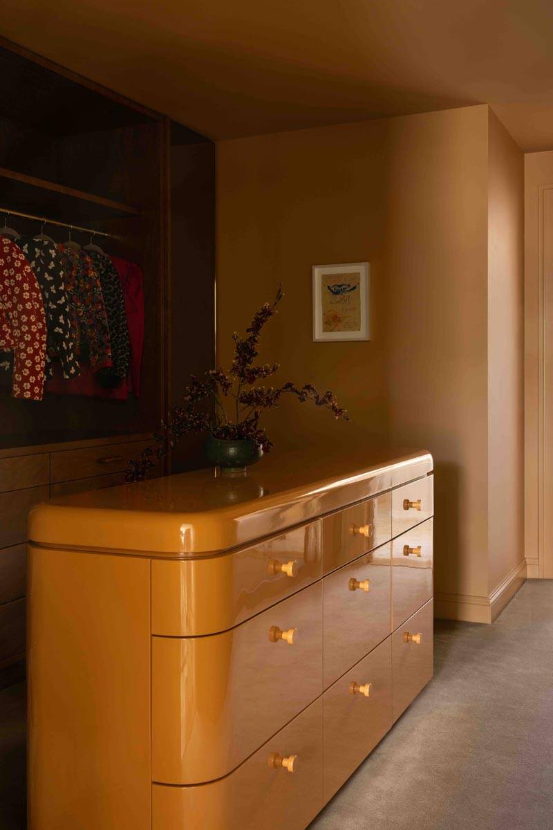 Warm mustard yellow dressing room or hallway space in a Boerum Hill townhouse location house from Love Locations, featuring a vintage-style curved wooden dresser.