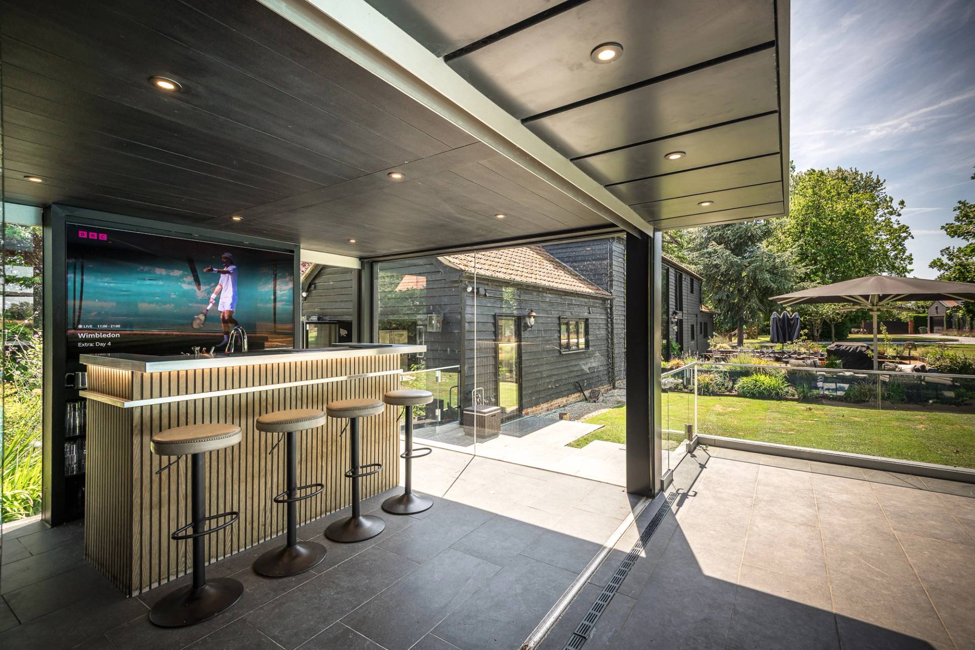 Luxury outdoor kitchen and garden bar location space with bar stools and integrated lighting for commercial use, Love Locations.