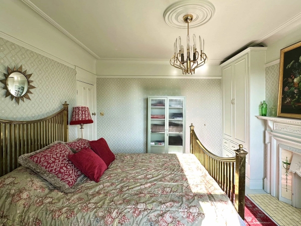 Edwardian master bedroom with brass bedstead, floral duvet, ceiling rose, and large sash windows, Love Locations N13.