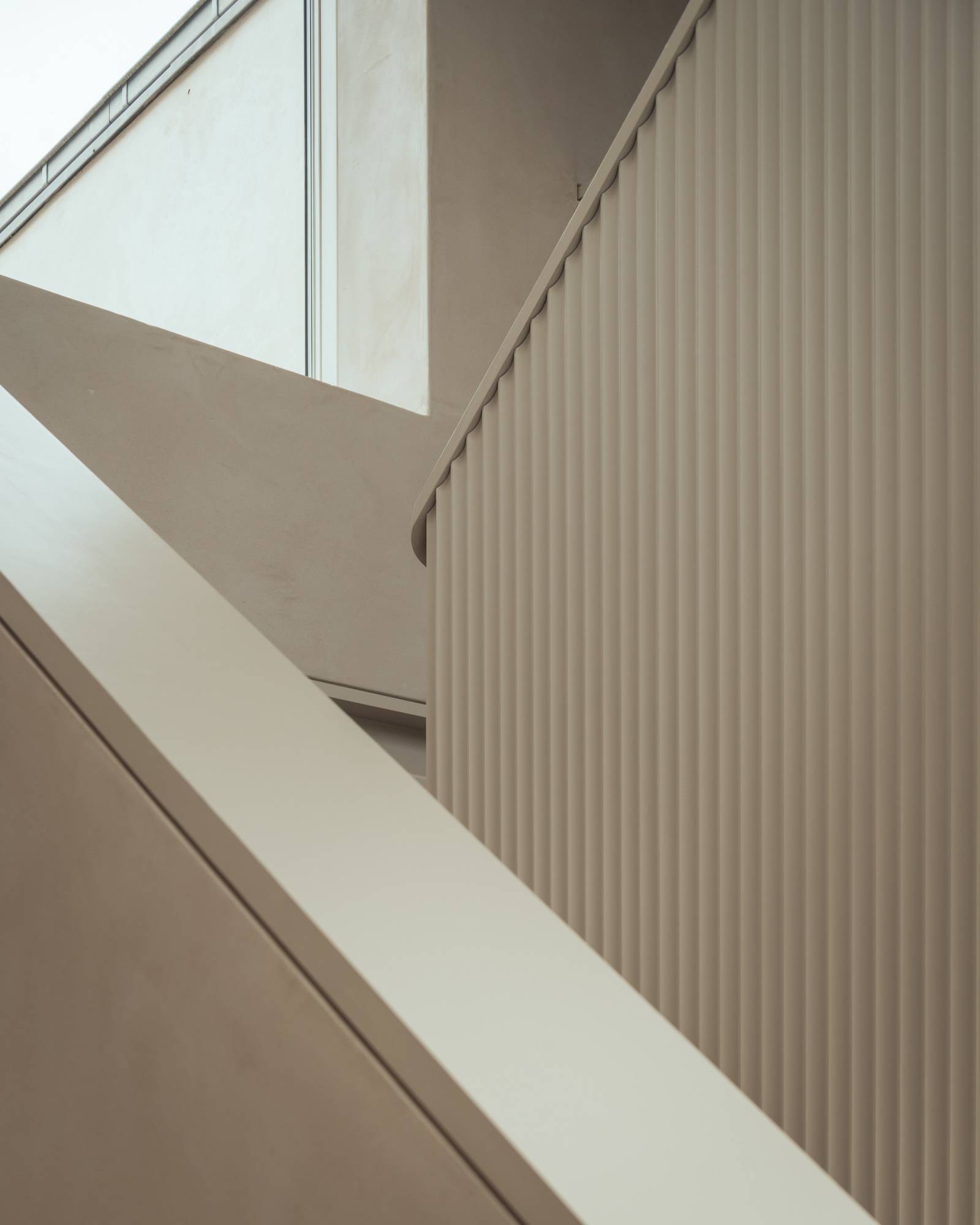 Architectural perspective looking up a geometric micro-cement staircase with fluted detail walls, Love Locations.
