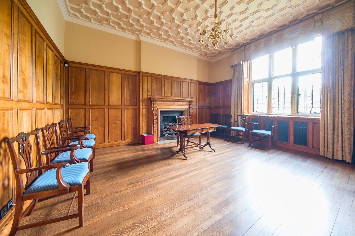 Historic dining room location house in Hertfordshire AL9 from Love Locations, featuring geometric ceiling plasterwork, half-height wood panelling, and blue upholstered dining chairs.