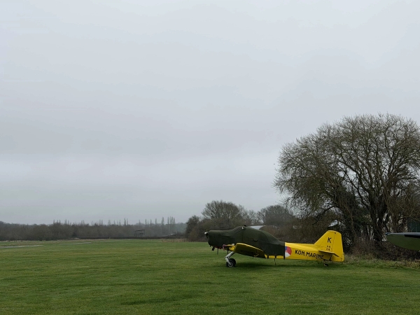 Bright yellow vintage training aircraft on a historic airfield grass strip, perfect for outdoor commercial photo shoots and brand campaigns, Love Locations