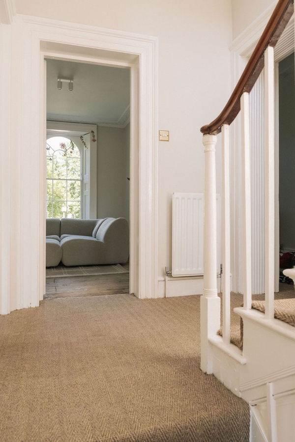 Staircase landing perspective looking back toward a bright open-plan reception room, Love Locations South London.