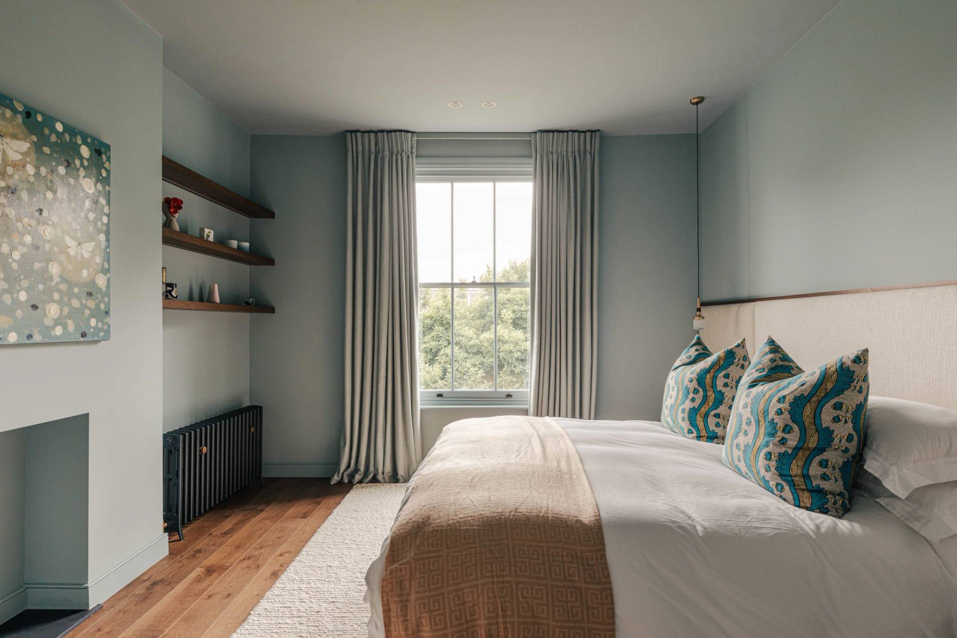 Serene master bedroom suite featuring light blue walls, neutral bed linens, and floating shelves, perfect for sleepwear brand ads, Love Locations SW13.