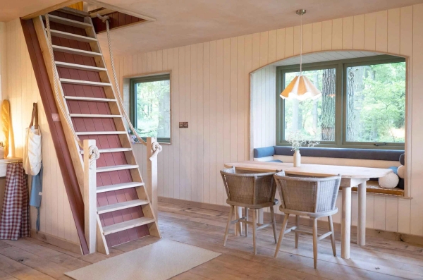 Crafted timber staircase steps leading up to an attic loft space next to a bright windowed dining alcove, Love Locations.