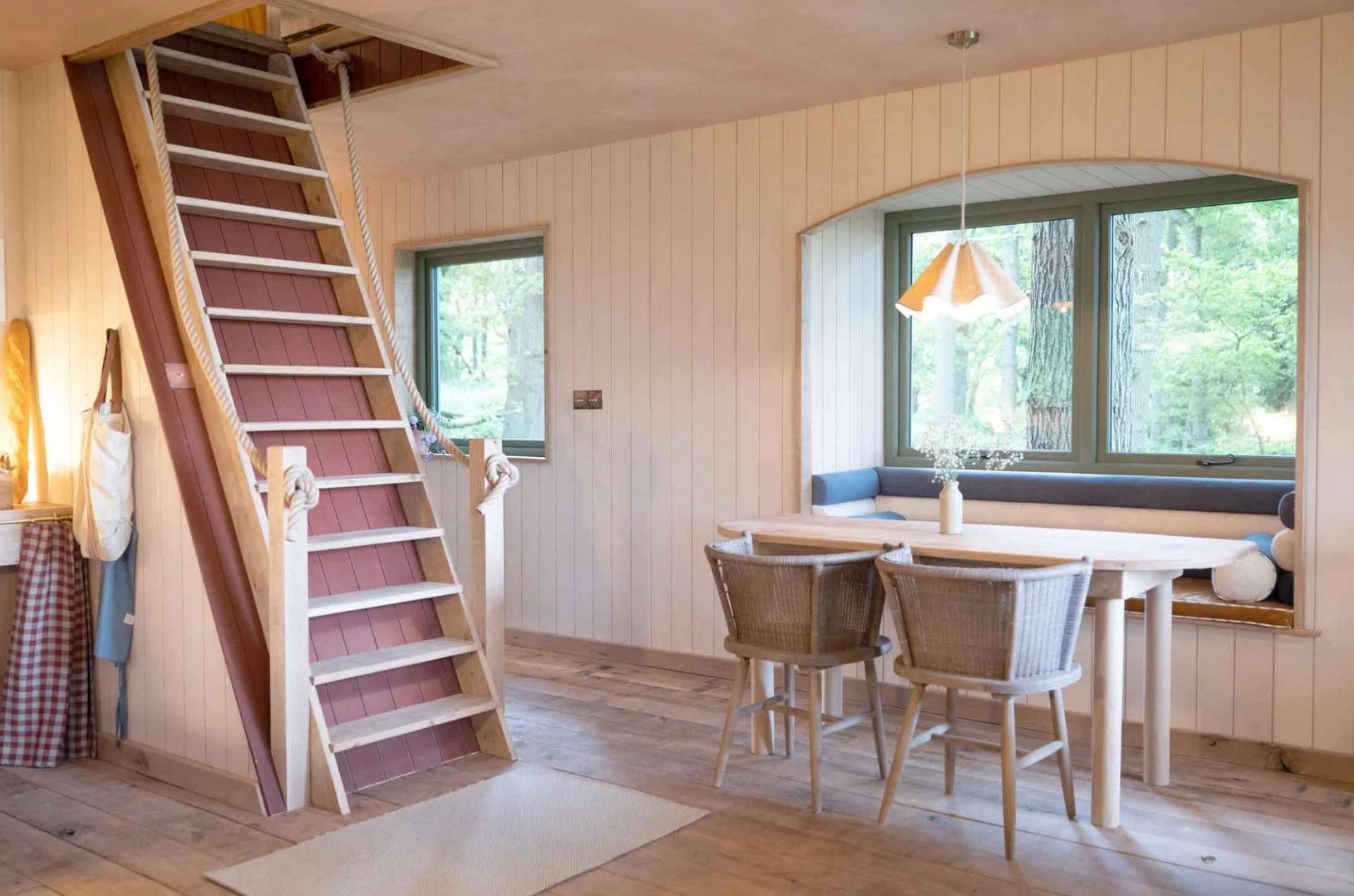 Crafted timber staircase steps leading up to an attic loft space next to a bright windowed dining alcove, Love Locations.