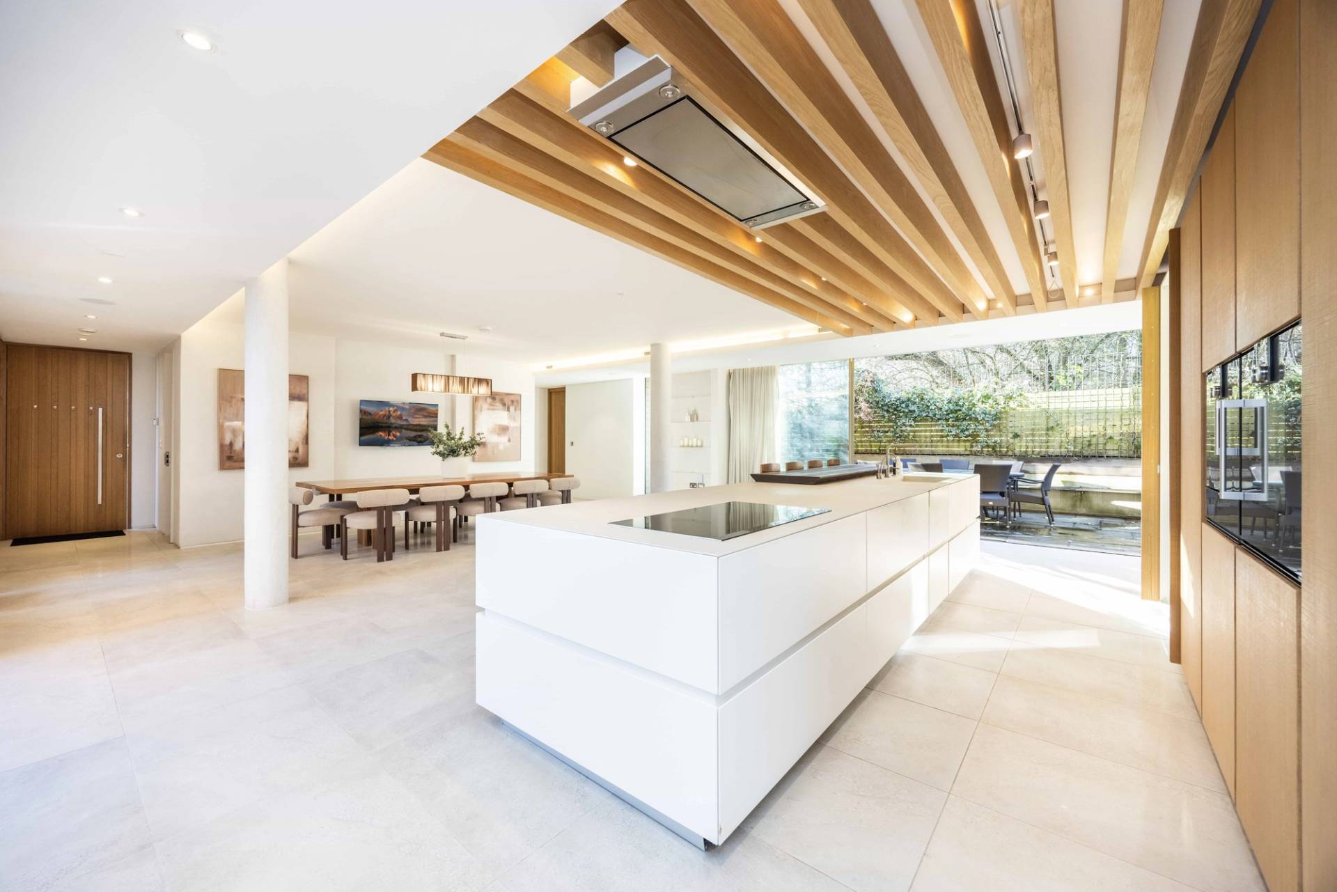 White kitchen island with gas hob set under modern wooden ceiling slats and ambient LED lighting, Love Locations WD7.
