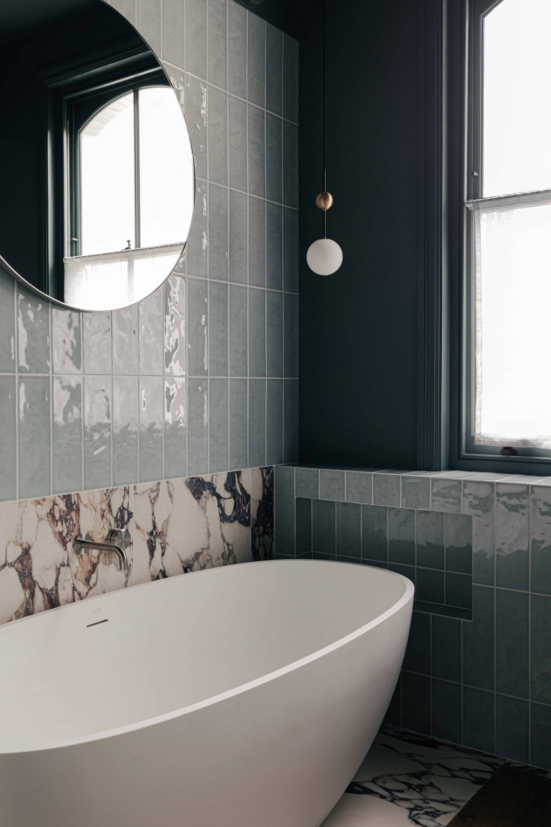 Glossy teal tiled bathroom wall set beside a freestanding oval soaking tub, perfect for skincare commercials, Love Locations.
