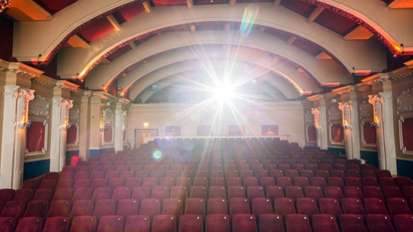 Cinematic lighting lens flare highlighting the grand arched ceiling and empty red velvet seats in The Ritzy Screen 1 in Brixton SW2 available through Love Locations.