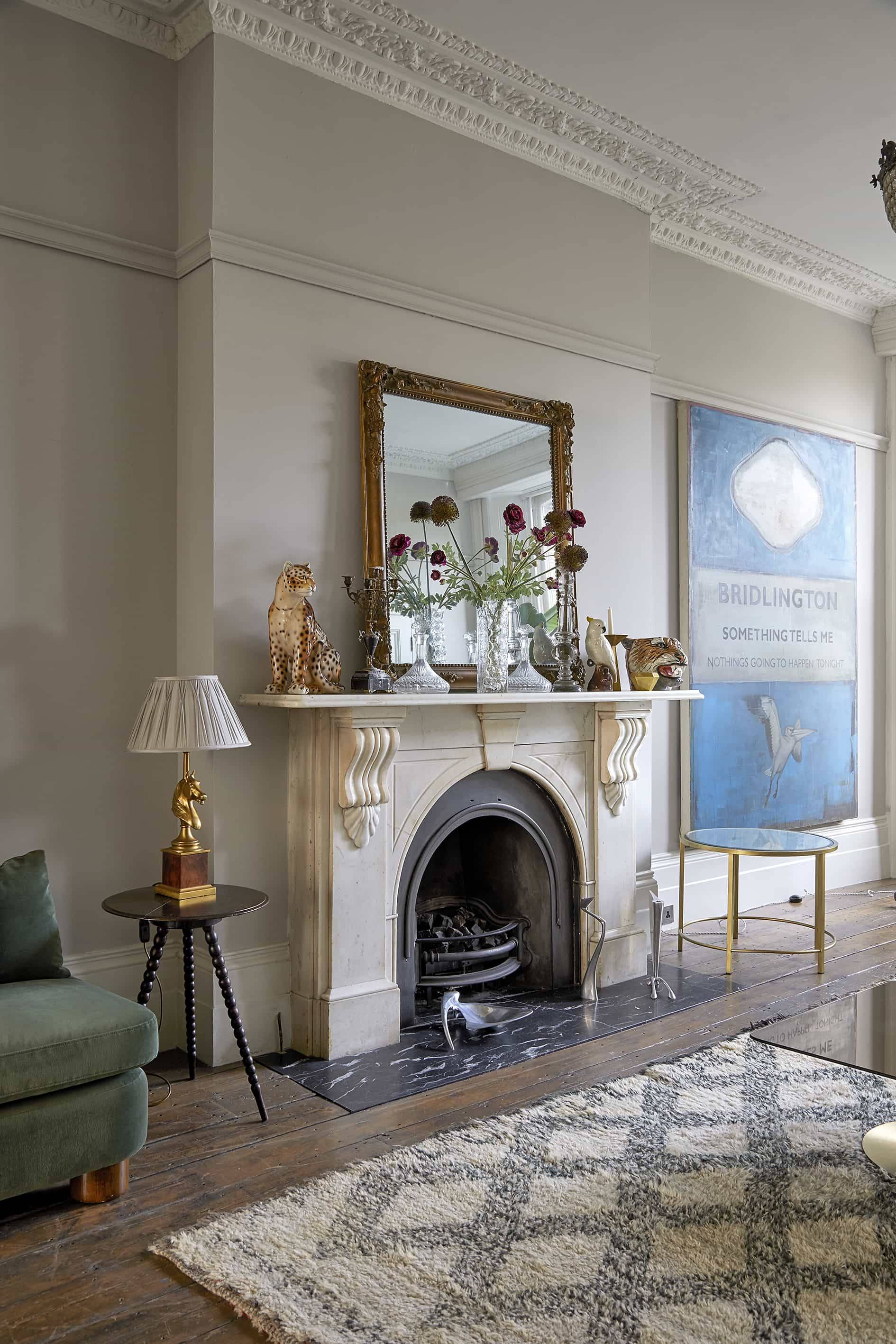 Formal living room with blue patterned sofa, bay window, large indoor palm plant, and brass mirrors, Love Locations N16.
