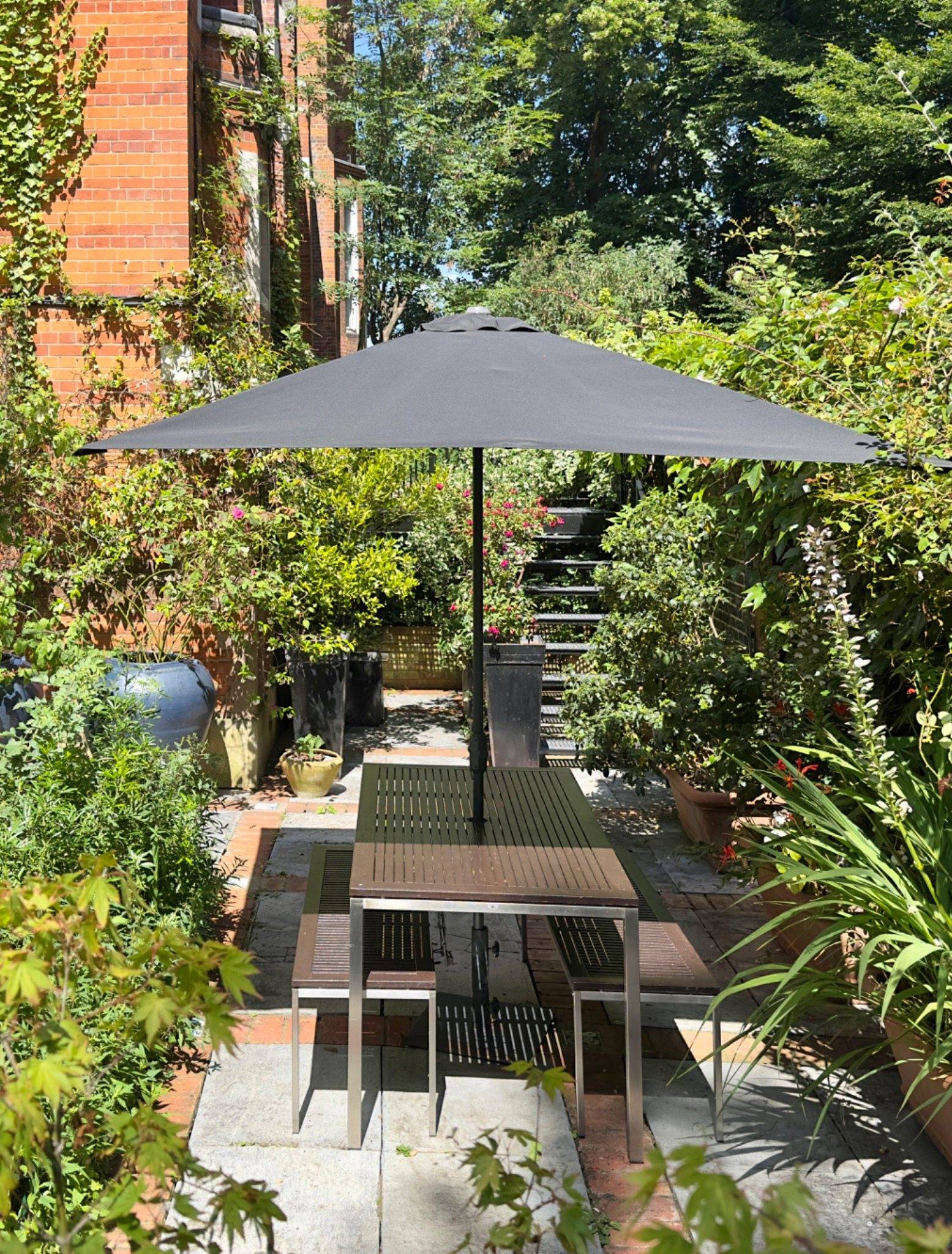 Secluded private courtyard terrace featuring outdoor dining furniture and parasol at a chapel location house in Oval SE5 via Love Locations.
