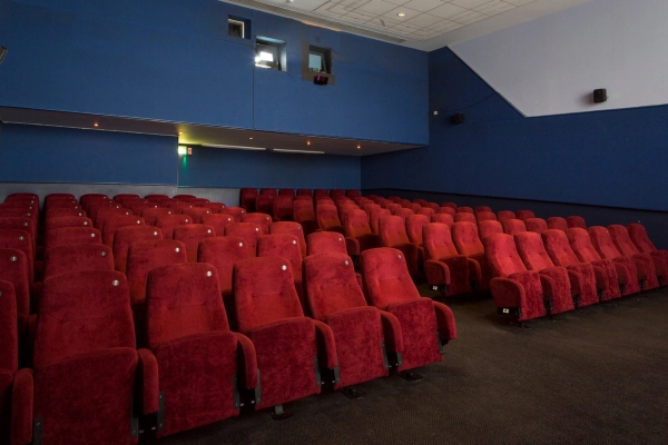 Rear perspective shot looking back across the empty red velvet seats toward the upper wall and projection booth in The Ritzy Screen 3 by Love Locations.