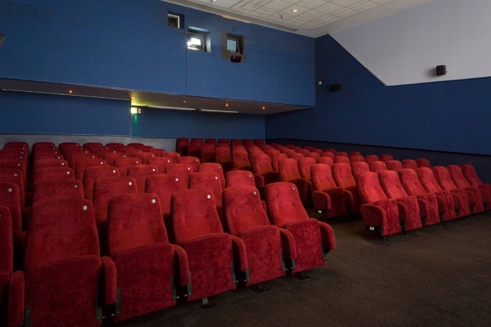 Rear perspective shot looking back across the empty red velvet seats toward the upper wall and projection booth in The Ritzy Screen 3 by Love Locations.
