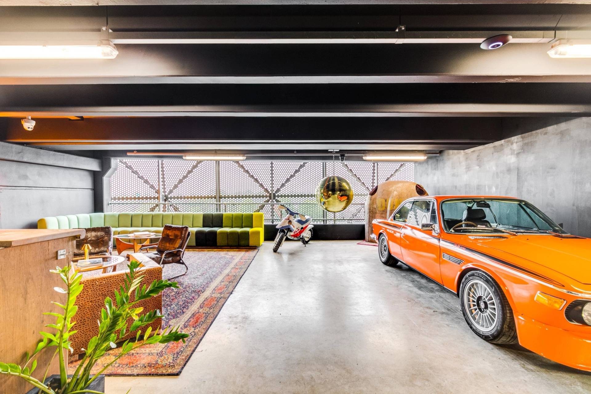 Open-plan car showroom photoshoot location in Brentford West London from Love Locations, showcasing polished concrete floors, retro seating, and classic vehicles.