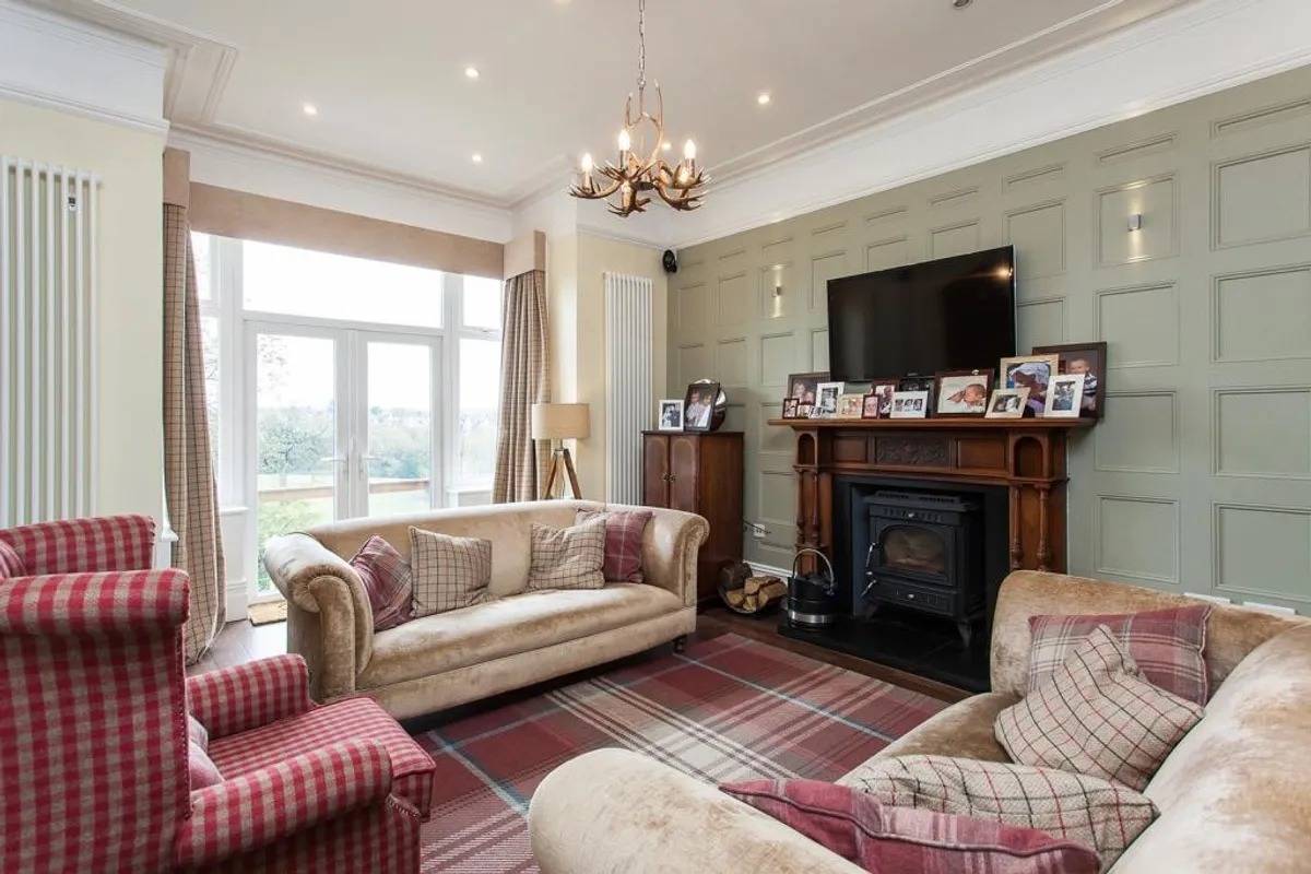 Characterful living room location house in Stockport SK6 from Love Locations, featuring sage green wall panelling, feature fireplace, and traditional bay window.