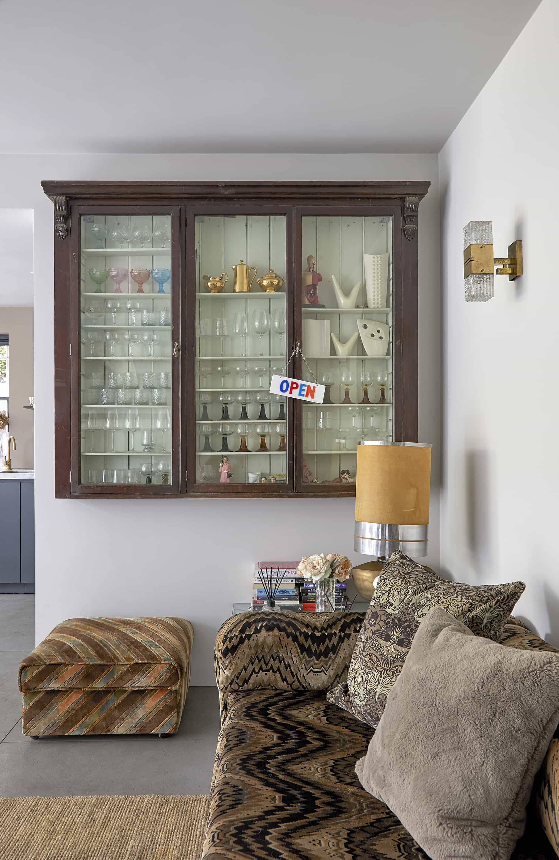 Vintage wall-mounted glass display cabinet set above tiger-print stools in a modern extension, Love Locations N16.