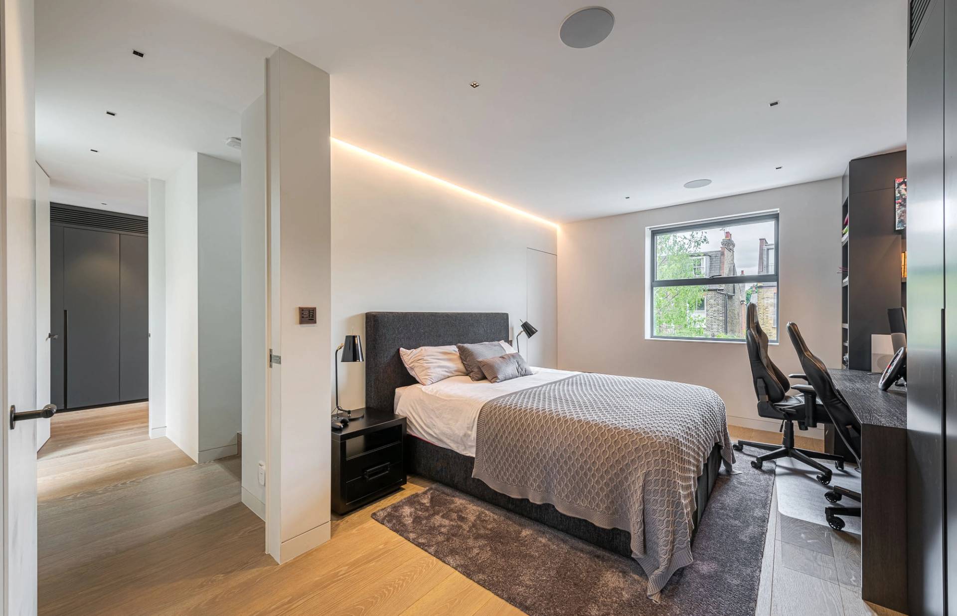 Modern guest bedroom featuring wood flooring, neutral bedding, and ensuite access, Love Locations SW11.