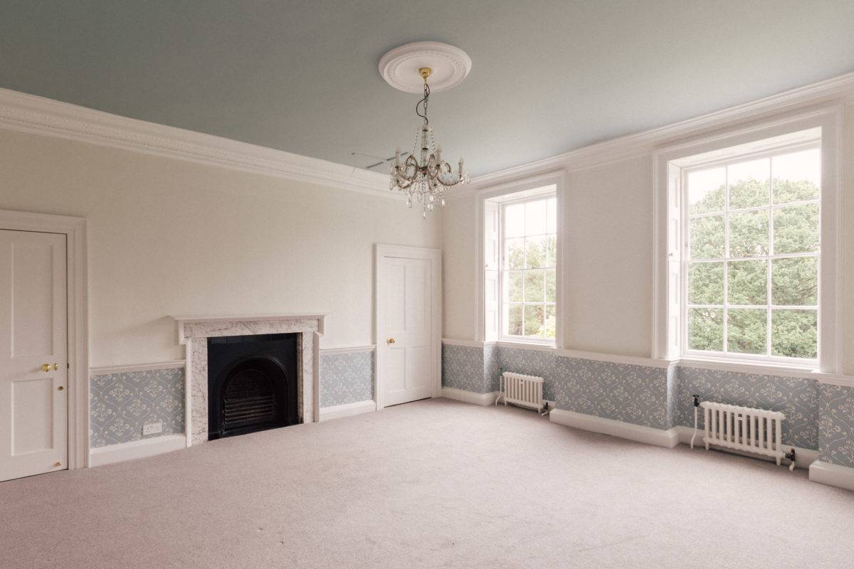 Spacious guest suite featuring light grey walls, patterned dado wallpaper, neutral carpet, and a period fireplace hearth, Love Locations SE15.