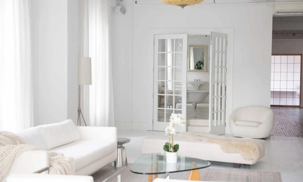 Open interior view looking past a minimalist living room toward classic white double doors in a New York loft studio, Love Locations.