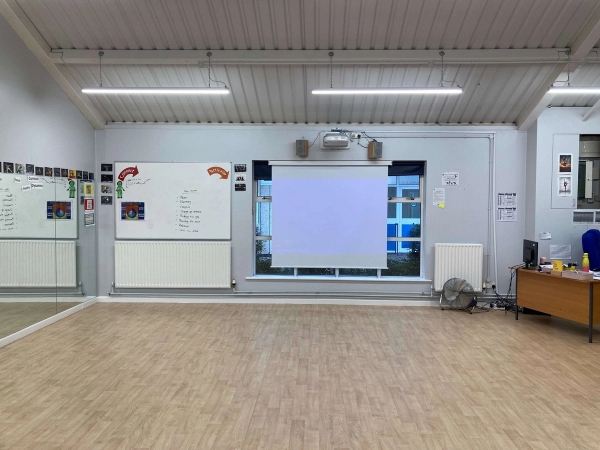 Love Locations school drama studio location Chelmsford: Rehearsal space featuring whiteboard displays, a projector screen, and a mirrored wall panel, tailored for corporate training videos and educational media.
