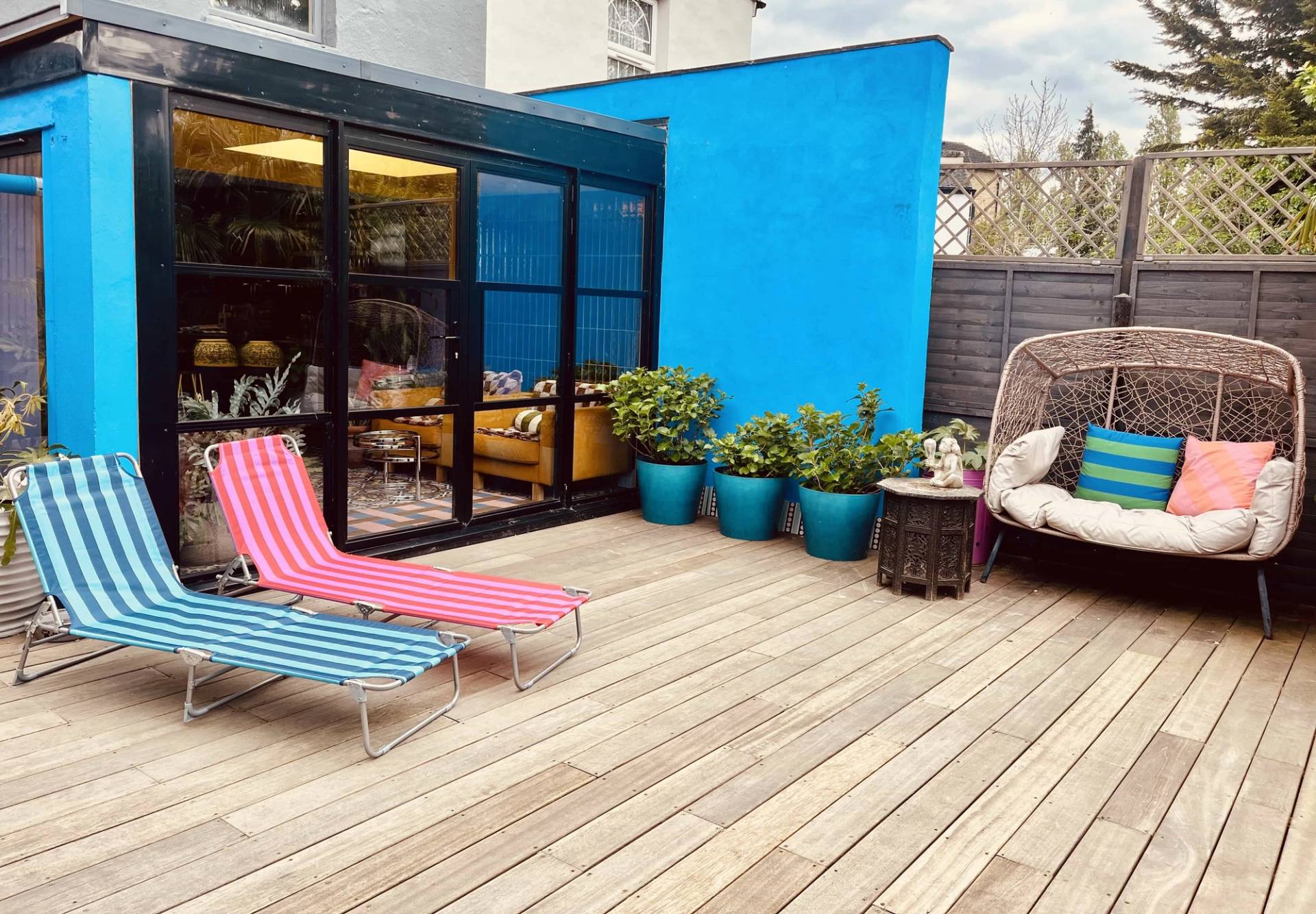 Pink and blue striped sun lounger set on an expansive timber garden deck, Love Locations SE6.