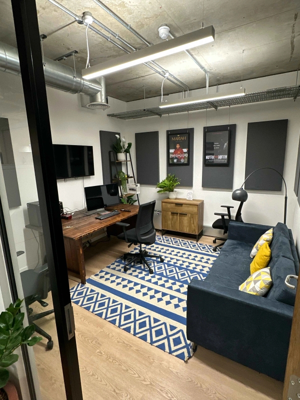 Small, intimate office space with a desk, TV, sofa, sideboard, modern artworks, and a patterned rug