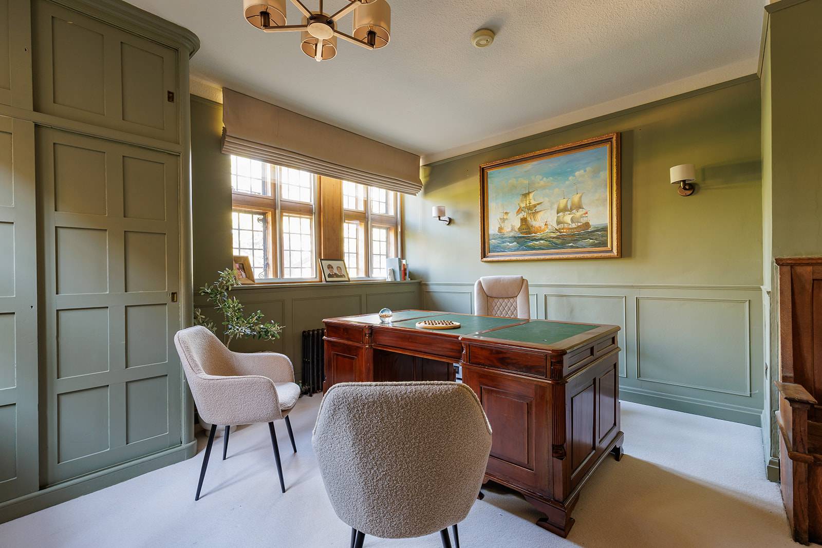 Executive home study office with olive green panelled walls, mahogany desk, and leather chairs, Love Locations RH13.