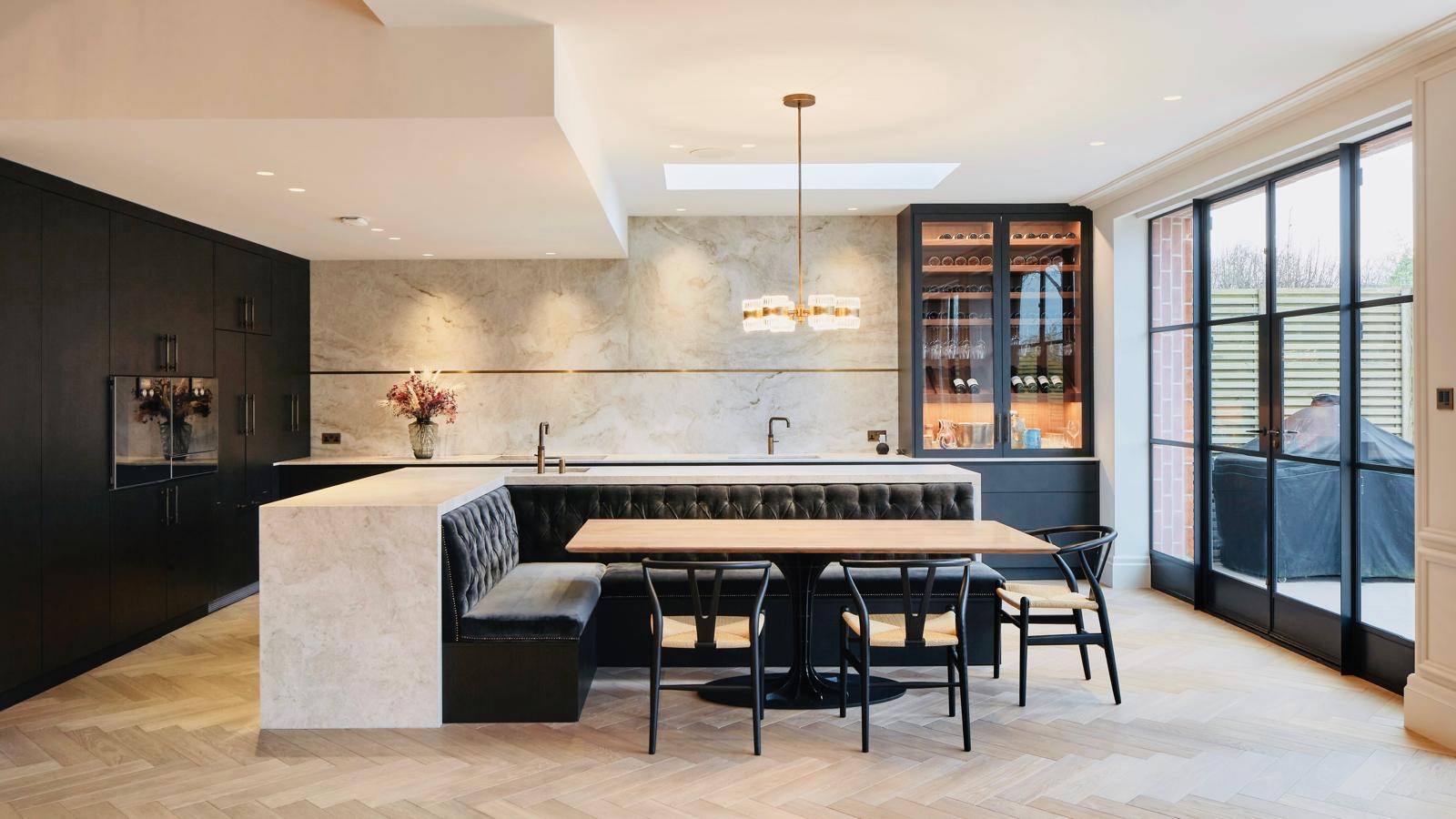 Open-plan dining booth and kitchen island set beneath a large roof skylight in Teddington, Love Locations TW11.