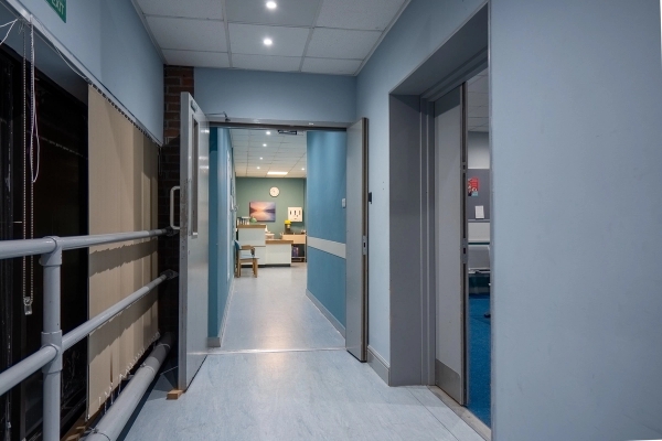 Hospital hallway transition with double swing doors and blue wall panelling, Love Locations UB4.