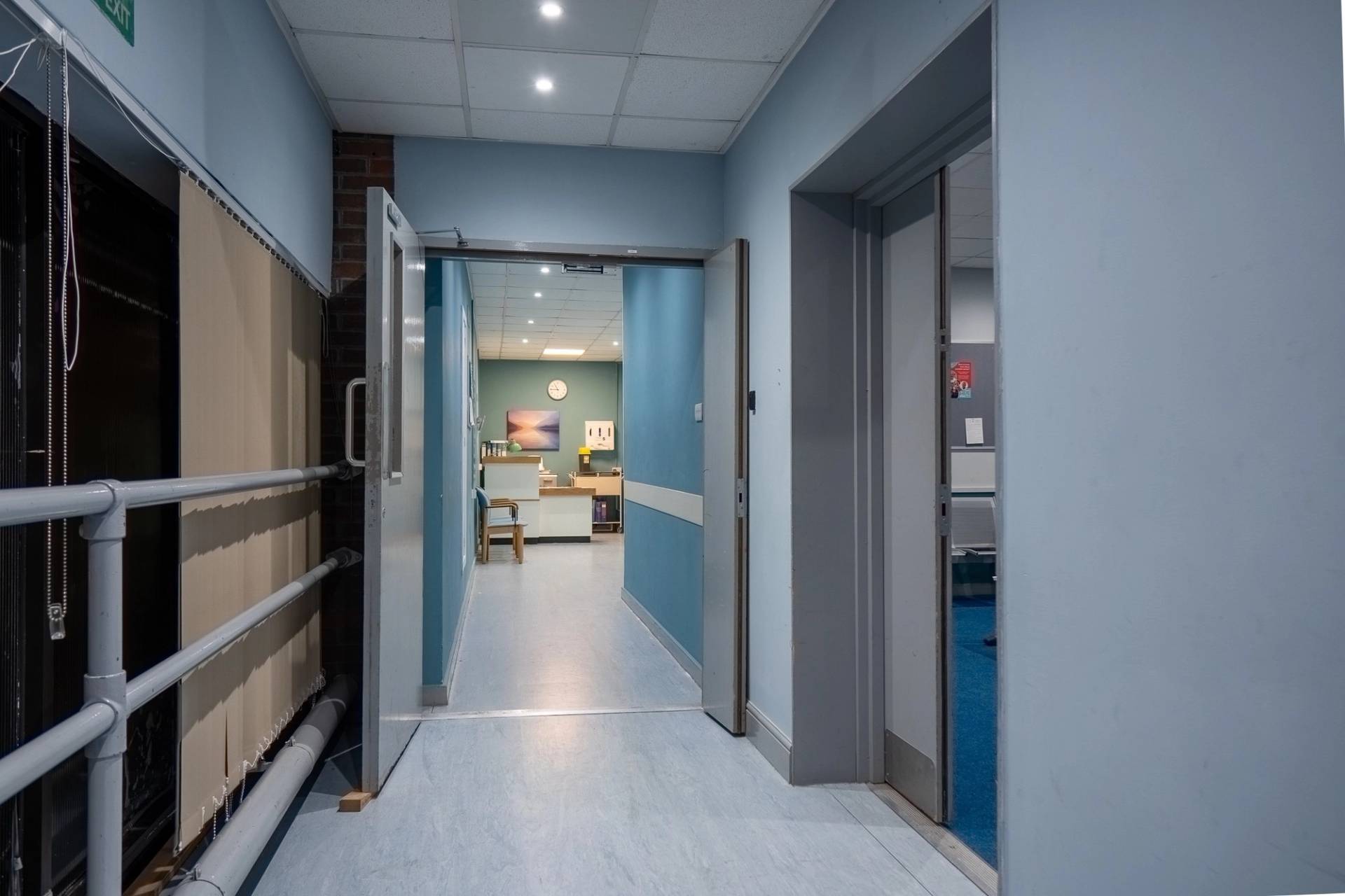 Hospital hallway transition with double swing doors and blue wall panelling, Love Locations UB4.