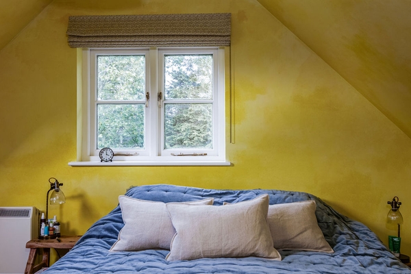 Attic bedroom with vaulted ceiling, feature window and colourful décor at Love Locations in Liss, Hampshire GU33.