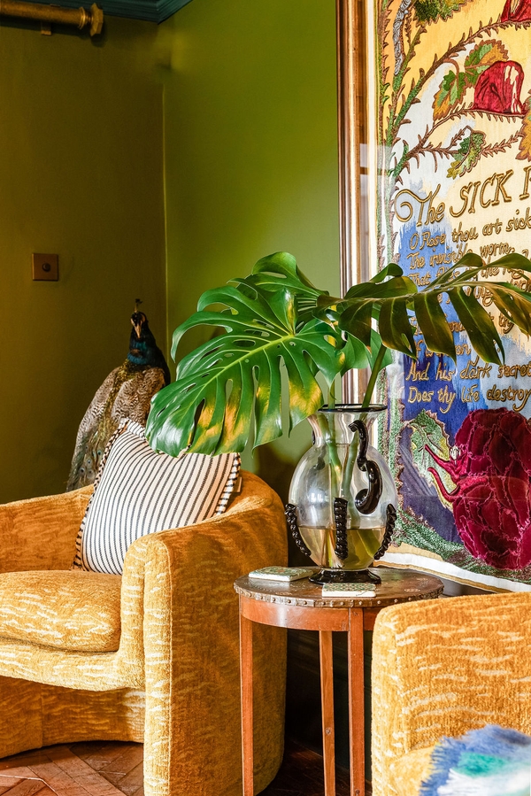 Sunlit green salon corner displaying a velvet armchair, large monstera houseplant, and dramatic artwork, a creative shoot setting curated by Love Locations.