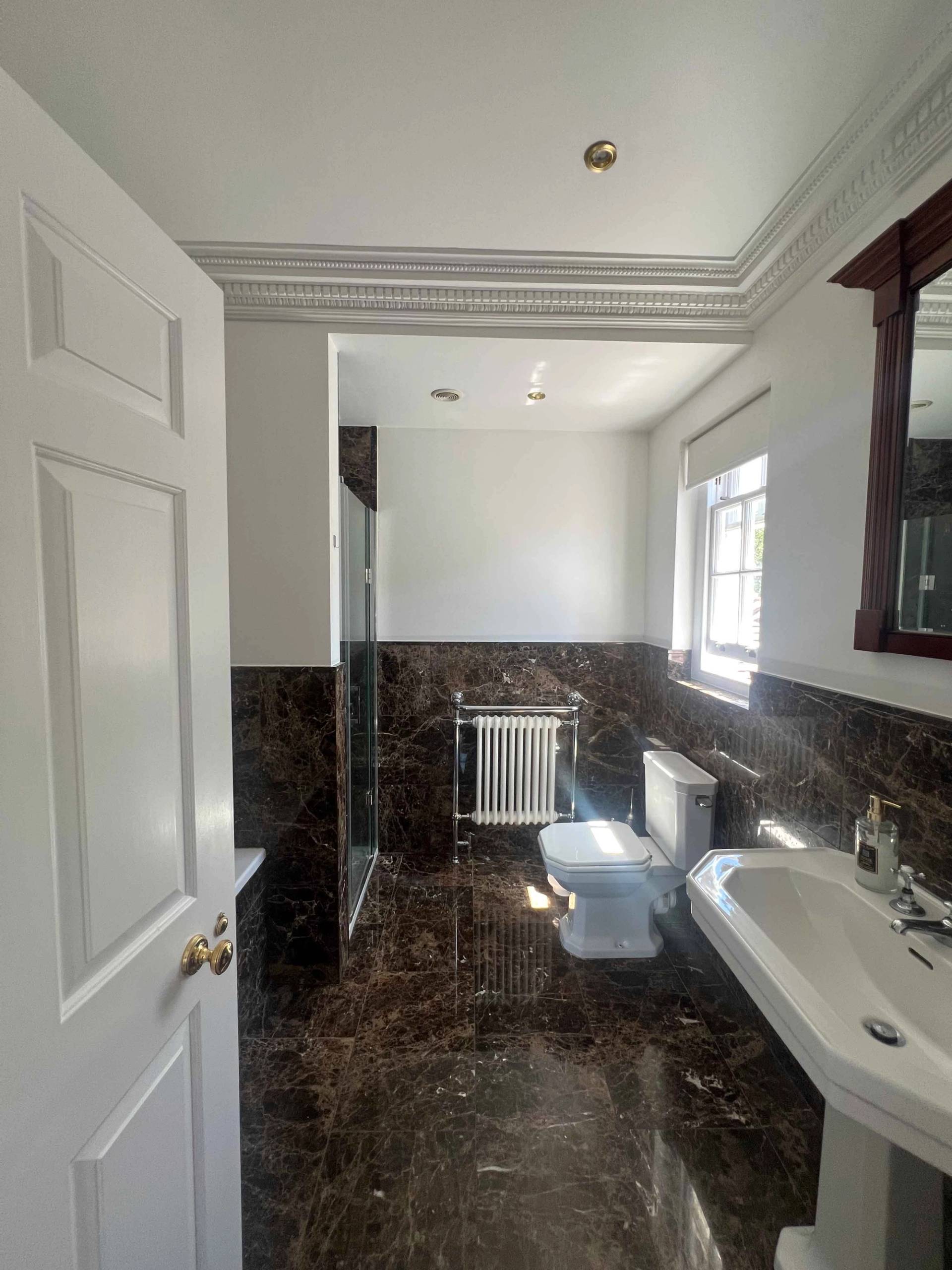 Ensuite bathroom with dark marble tile vanity surround, white porcelain sink, and walk-in shower, Love Locations BR7.