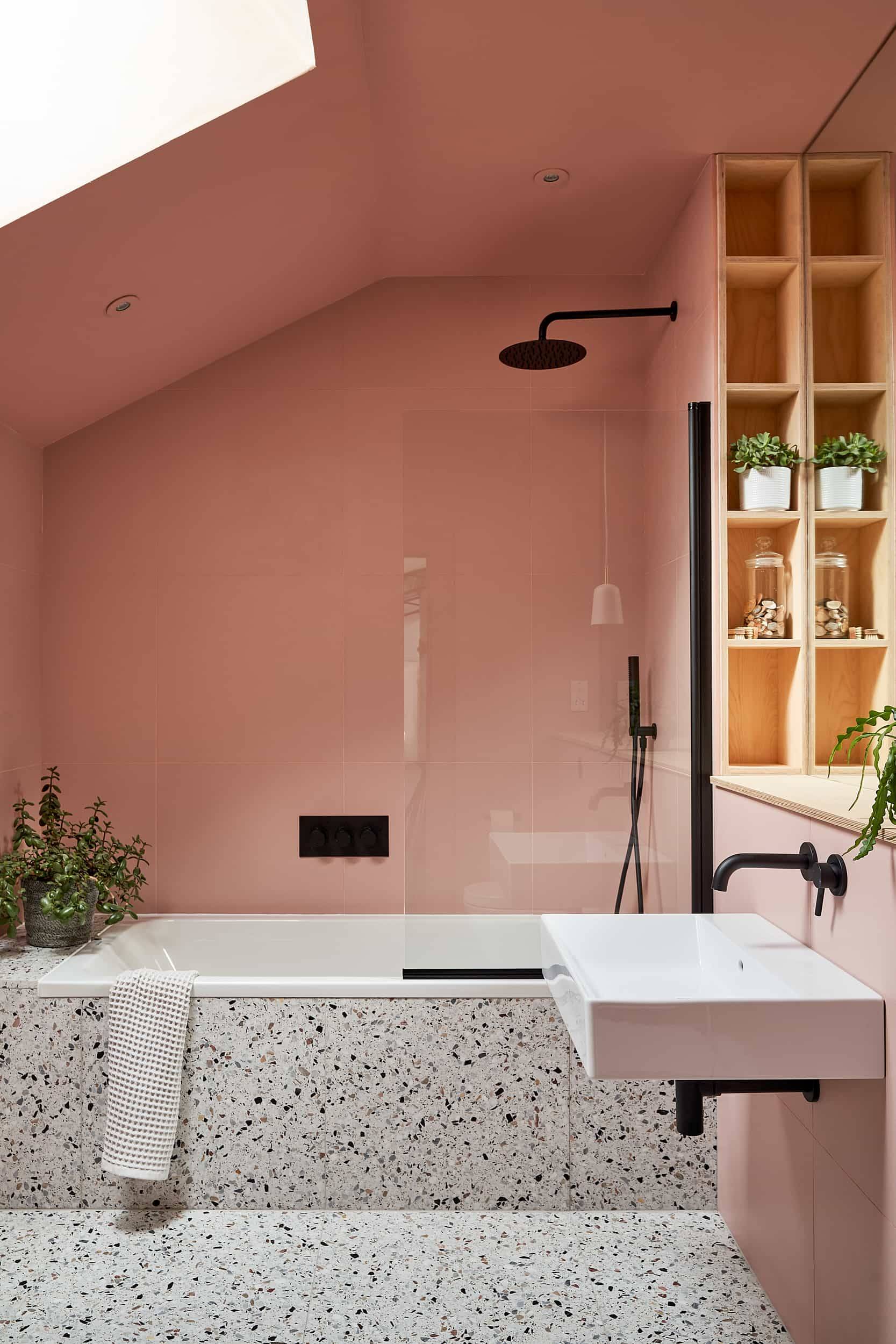Terracotta pink bathroom featuring a freestanding white bathtub, terrazzo tile floor, and brass shower fixtures, Love Locations IP30.