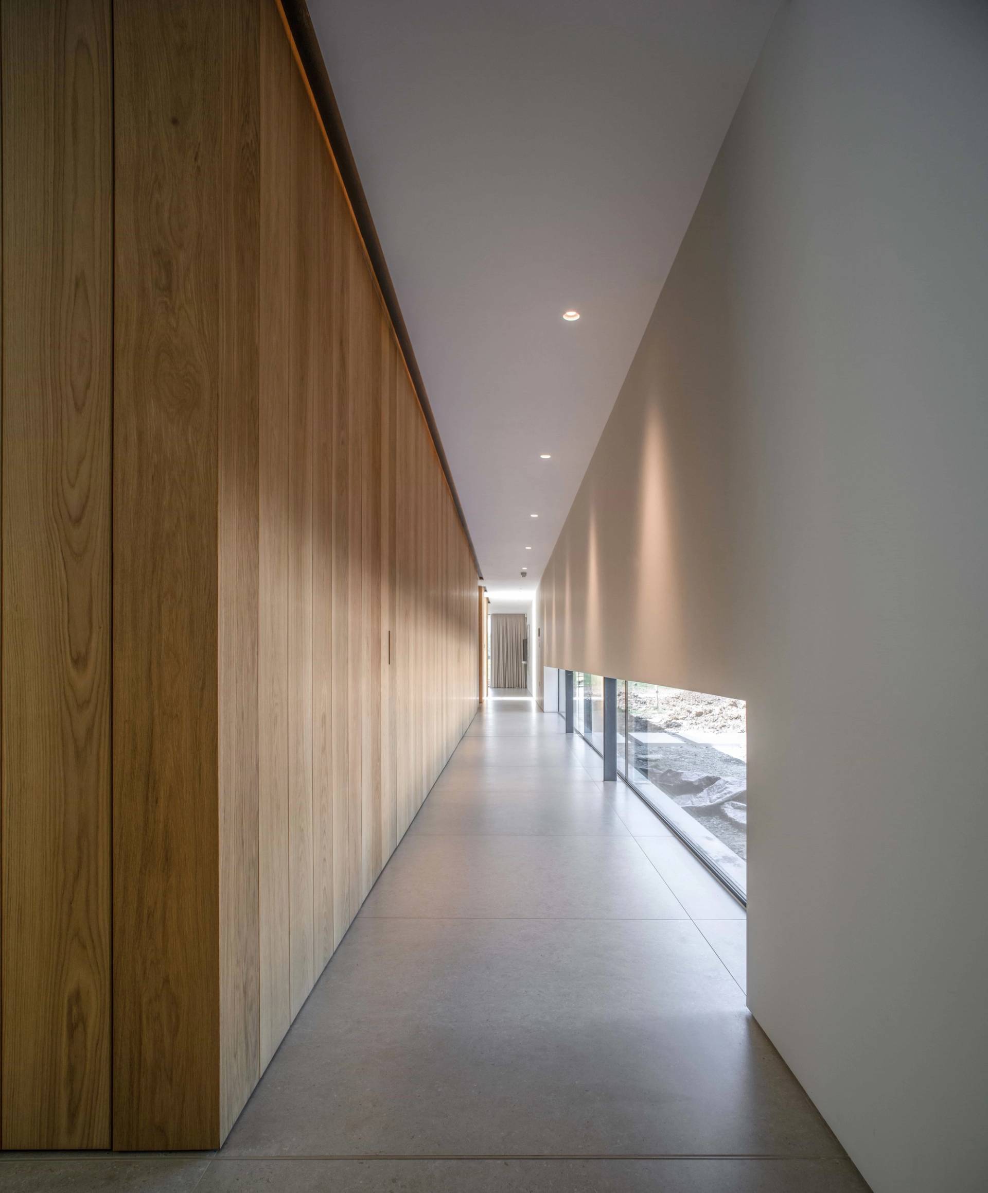 Sleek interior corridor showcasing floor-to-ceiling timber cladding, recessed lighting, and seamless minimalist architecture in Fryerning, Love Locations.