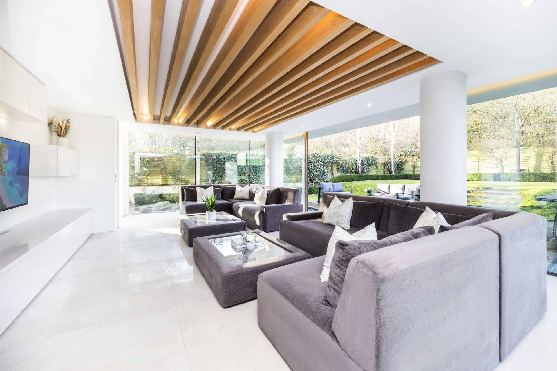 Luxury reception room featuring a slatted wooden ceiling, velvet sectional sofa, and glass coffee tables, Love Locations WD7.