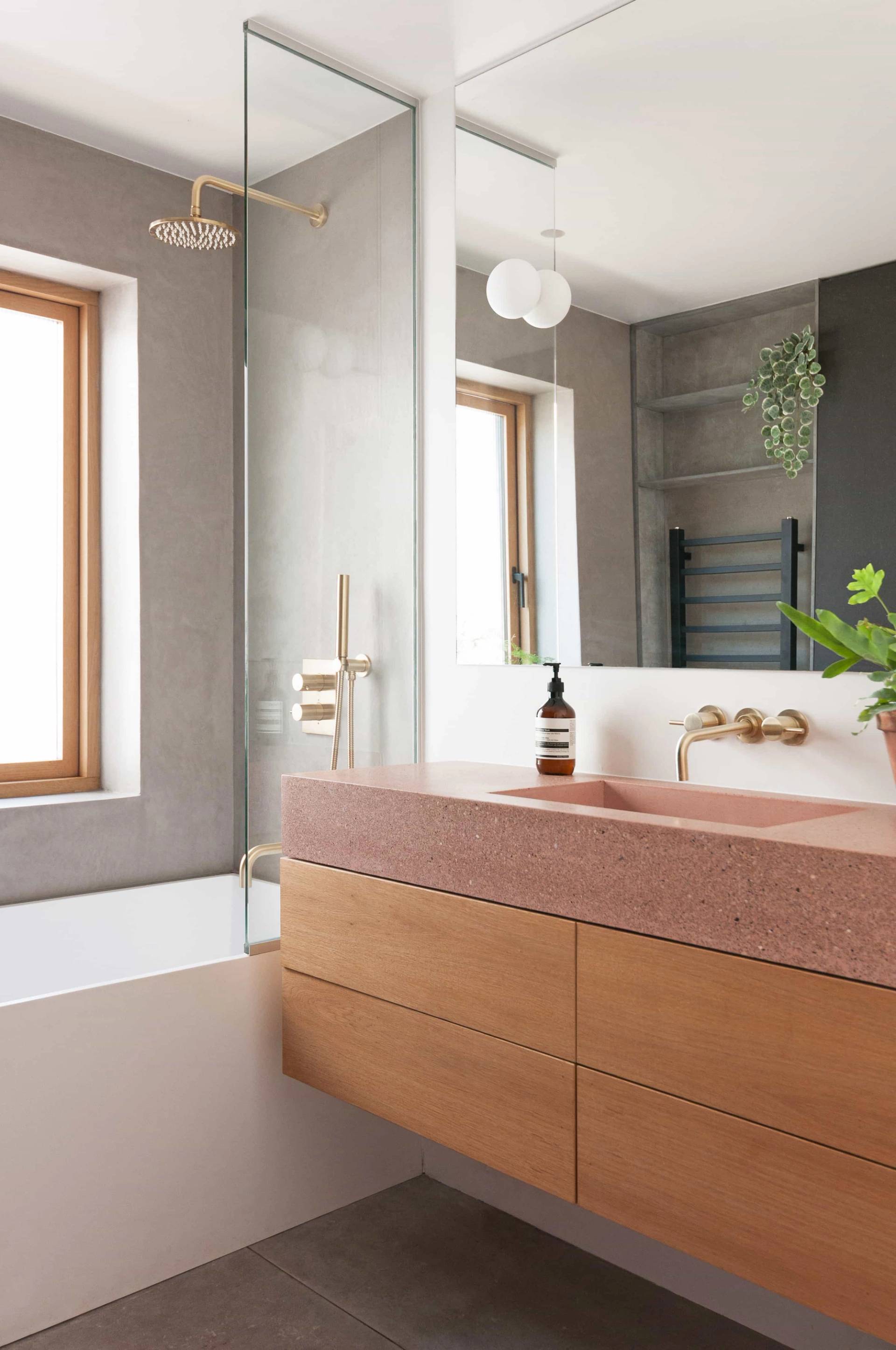 Terrazzo and light wood vanity bathroom location in Hackney London N16 from Love Locations, displaying a white bathtub, micro-cement walls, and large windows.